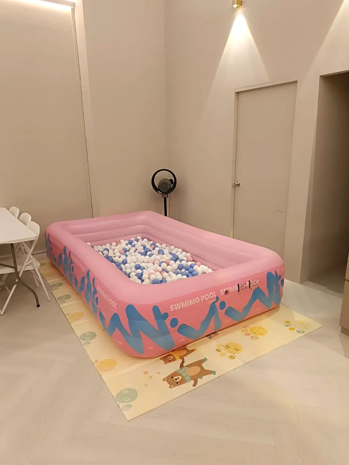 A pink ball pit set up on the floor of the hall