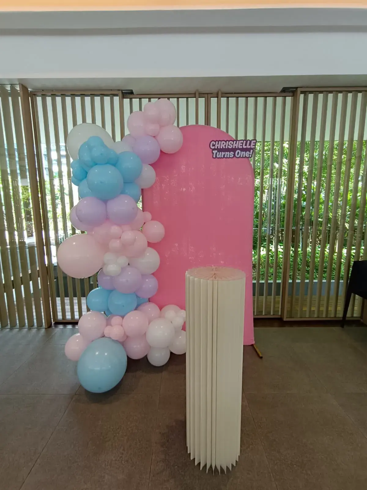 A pink and blue balloon arch against an arched backdrop